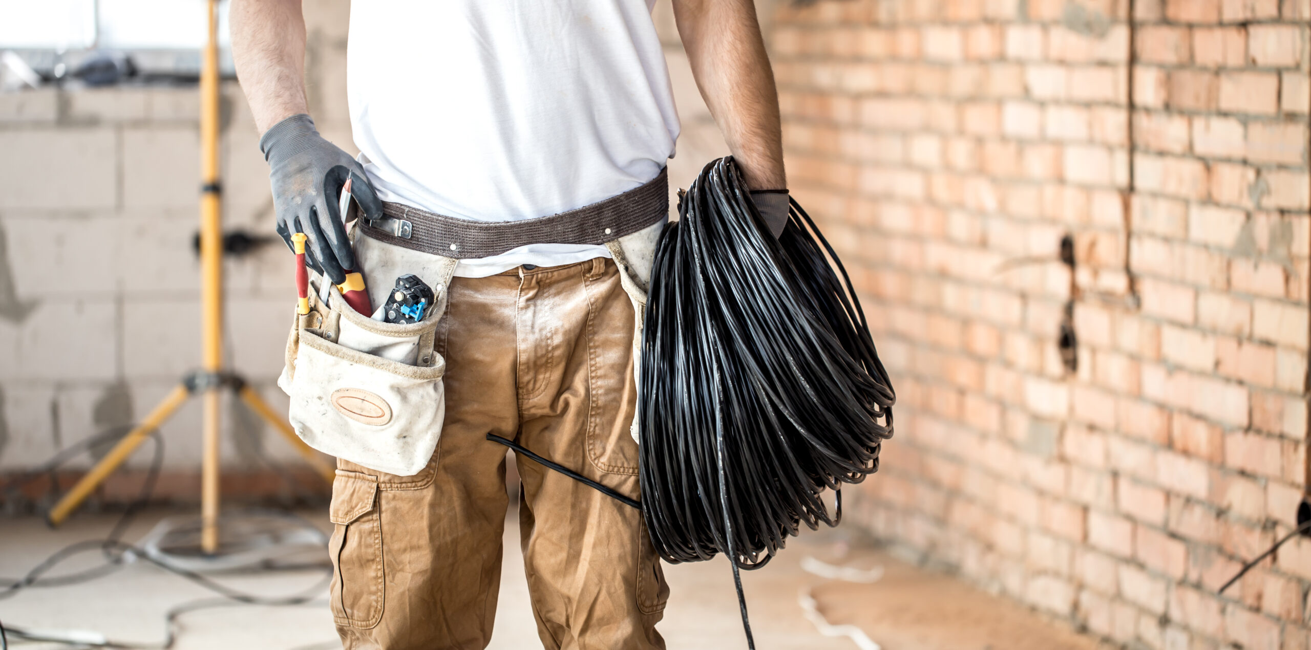 Electrician with tools, working on a construction site.